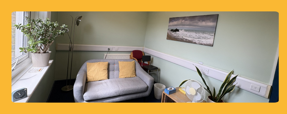 Comfortable therapy room in Islington North London featuring a sofa, indoor plants, and calming wall art for a safe consulting environment.